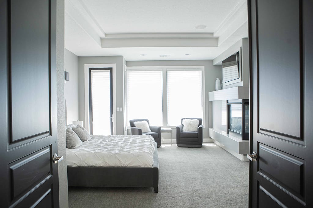 master bedroom interior with white bed and gray chairs