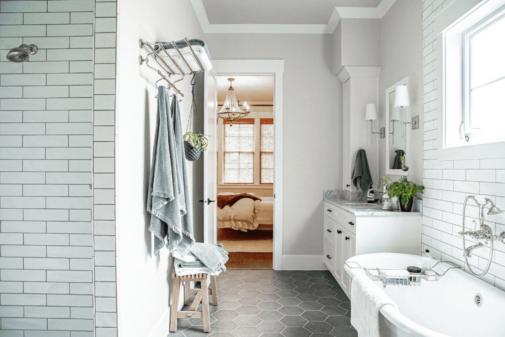 A master bedroom with a subway tiled shower, free standing tub and marble topped vanity.