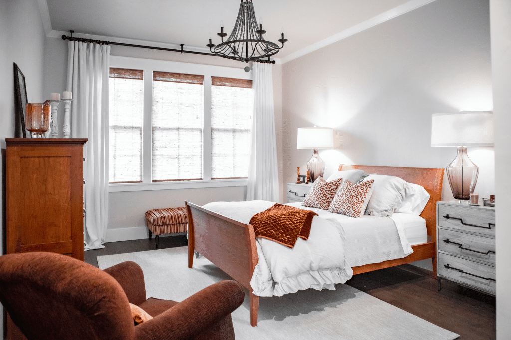 A master bedroom with a sleigh bed, white and rust colored bedding.