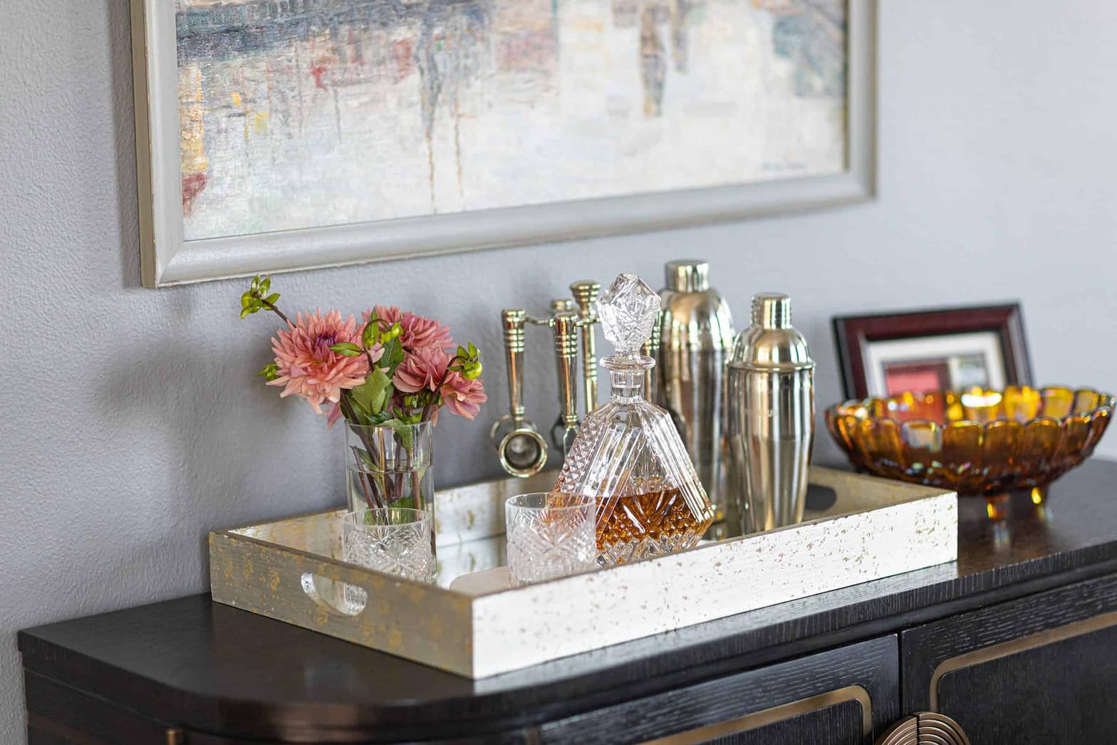 Stylish home bar with glassware, flowers, and decorative bottles.
